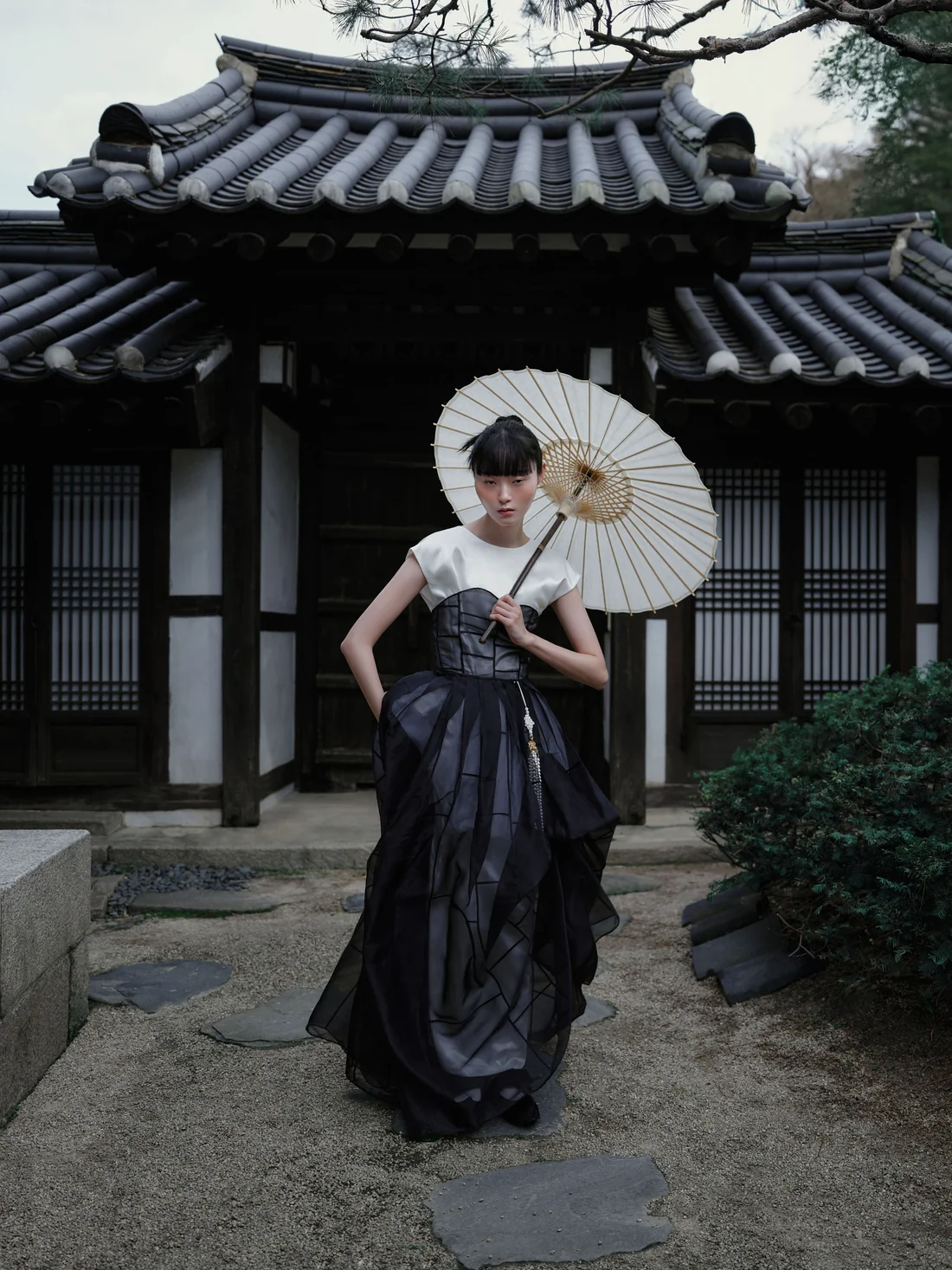 Modelo de hanbok moderno com sombrinha de papel diante de uma casa tradicional coreana, retrato de Seokjoo Shim em Seul