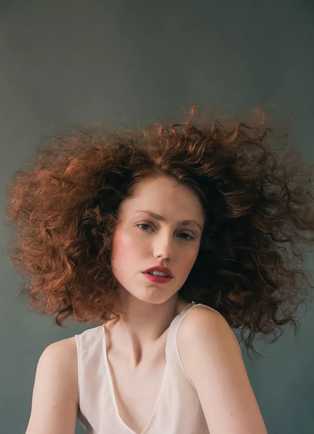 Modelo de cabelo ruivo cacheado em fundo verde, retrato de Leandro Ramos em São Paulo